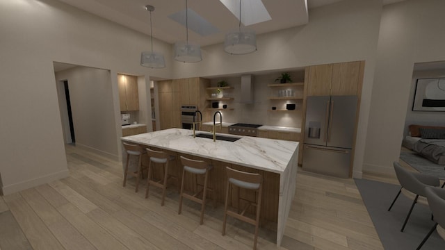 kitchen featuring sink, a kitchen island with sink, stainless steel appliances, decorative light fixtures, and light wood-type flooring