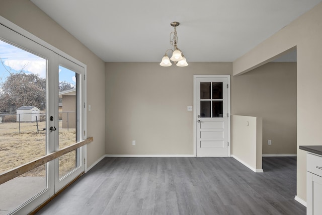 unfurnished dining area with a notable chandelier, wood-type flooring, and french doors