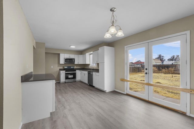 kitchen featuring sink, white cabinetry, stainless steel appliances, decorative light fixtures, and light wood-type flooring