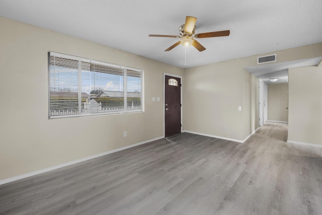 spare room with ceiling fan, light hardwood / wood-style flooring, and a textured ceiling