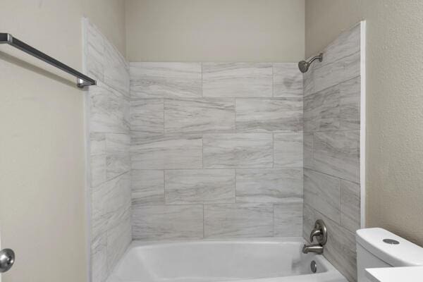 bathroom with toilet and tiled shower / bath