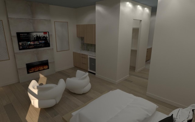 living area featuring beverage cooler, light wood-style flooring, a warm lit fireplace, and baseboards