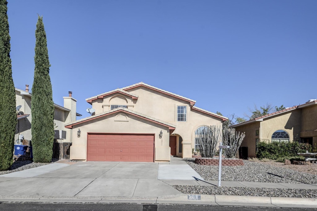 mediterranean / spanish house featuring a garage, concrete driveway, and stucco siding