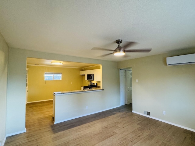 kitchen with an AC wall unit, wood finished floors, visible vents, and appliances with stainless steel finishes