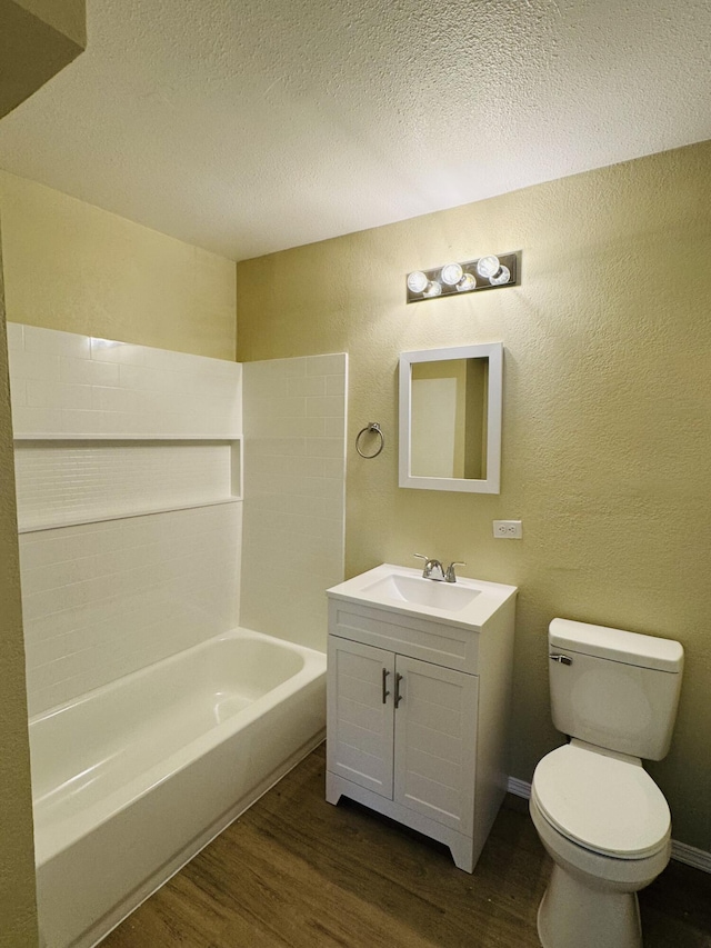 full bath with toilet, a textured ceiling, wood finished floors, vanity, and a textured wall