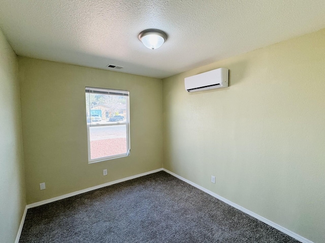 unfurnished room featuring visible vents, dark carpet, a wall mounted AC, and baseboards