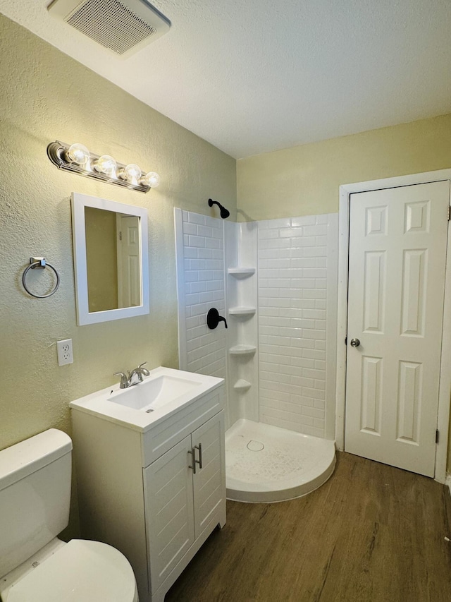 bathroom with visible vents, a shower stall, toilet, wood finished floors, and vanity