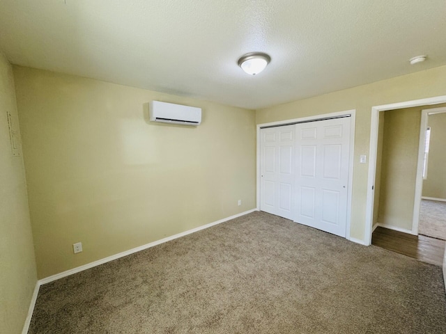 unfurnished bedroom featuring baseboards, carpet, a closet, and a wall mounted AC