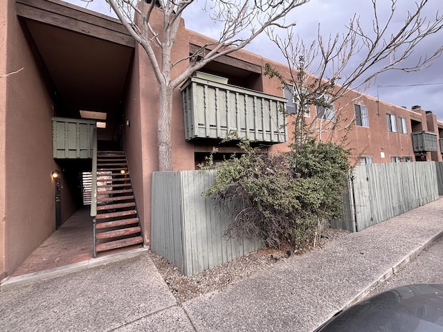 view of home's exterior featuring fence, stairway, and stucco siding