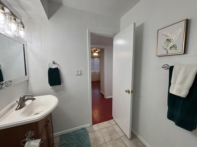 bathroom featuring tile patterned flooring, baseboards, vanity, and a textured ceiling