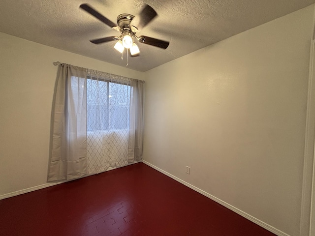 spare room with a ceiling fan, a textured ceiling, and baseboards