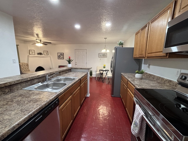 kitchen featuring brown cabinetry, hanging light fixtures, brick floor, stainless steel appliances, and a sink