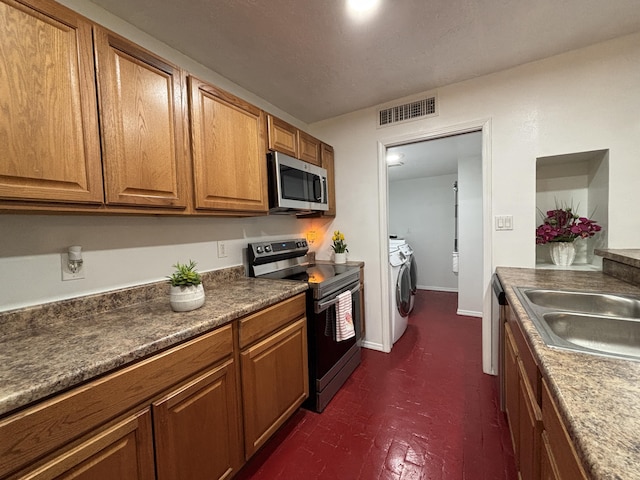 kitchen with stainless steel appliances, separate washer and dryer, a sink, visible vents, and brown cabinets