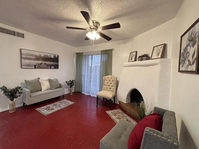 living area featuring finished concrete flooring, a ceiling fan, visible vents, and a textured ceiling