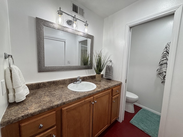 bathroom with toilet, vanity, and visible vents