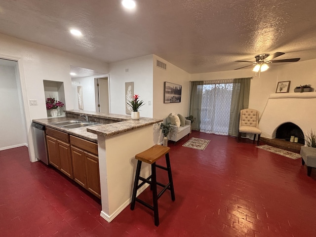 kitchen featuring a breakfast bar area, a sink, visible vents, open floor plan, and dishwasher