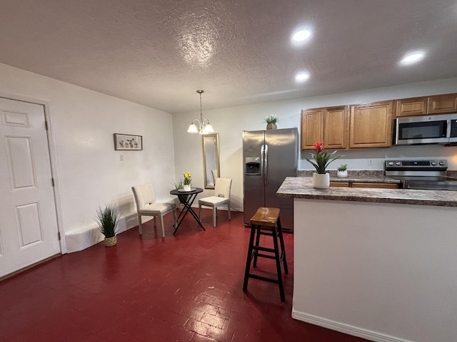 kitchen with stainless steel appliances, dark countertops, hanging light fixtures, a chandelier, and a kitchen breakfast bar