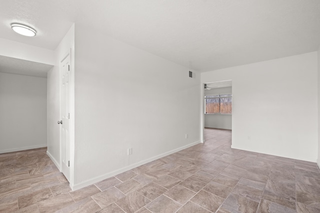 empty room with baseboards, visible vents, and a textured ceiling