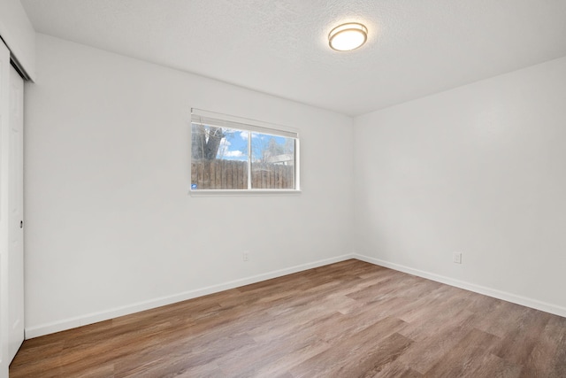 unfurnished bedroom featuring a closet, a textured ceiling, and light hardwood / wood-style flooring