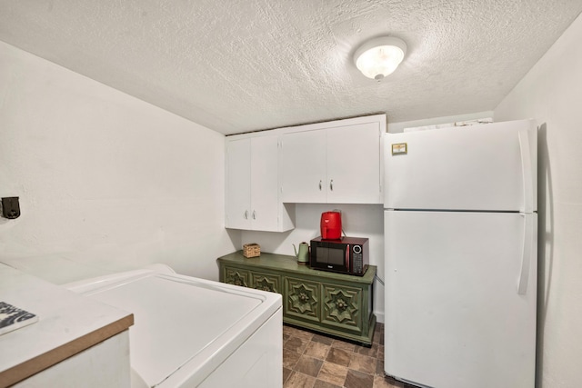 kitchen featuring washer / clothes dryer, a textured ceiling, white fridge, and white cabinets