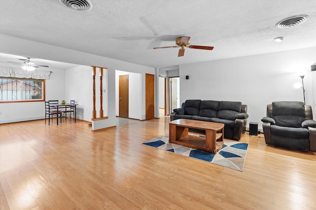 living room featuring ceiling fan, a textured ceiling, and light hardwood / wood-style flooring