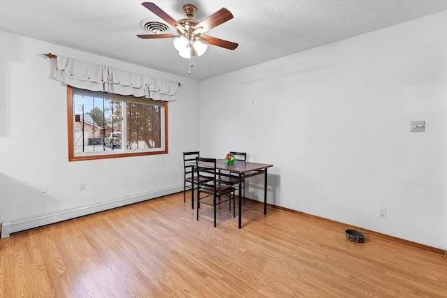 dining room featuring ceiling fan, a textured ceiling, baseboard heating, and light hardwood / wood-style floors