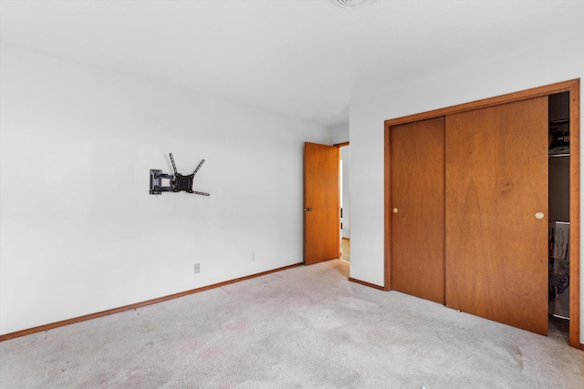 unfurnished bedroom featuring light carpet and a closet