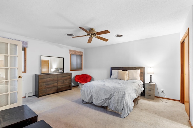 bedroom with ceiling fan, light carpet, and a textured ceiling