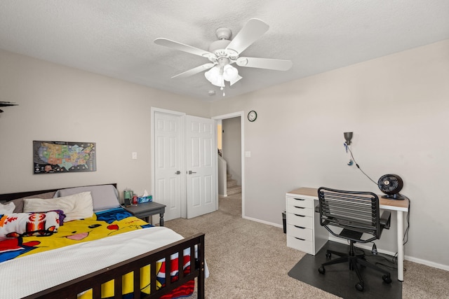 carpeted bedroom featuring ceiling fan and a textured ceiling