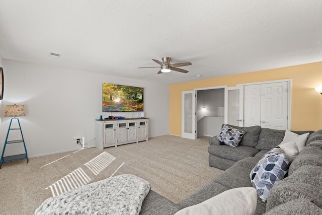 carpeted living room with ceiling fan and a textured ceiling