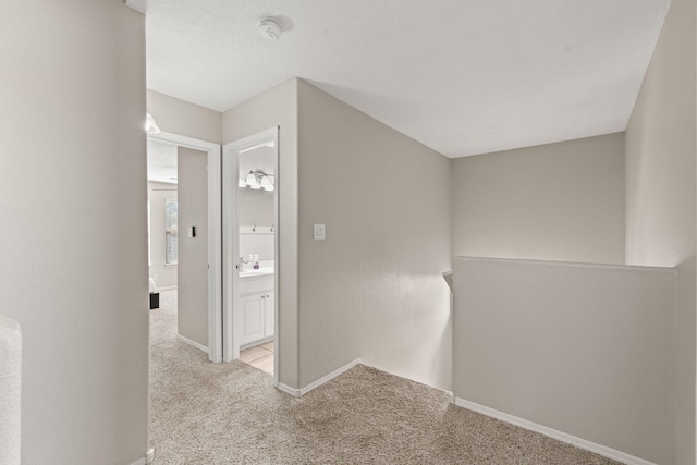 hallway featuring light colored carpet and sink