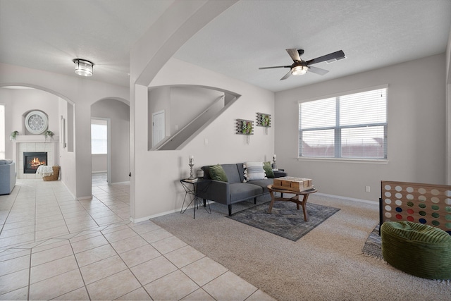 living room with light tile patterned flooring, a tiled fireplace, a textured ceiling, and a wealth of natural light