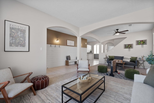 tiled living room with ceiling fan and a textured ceiling