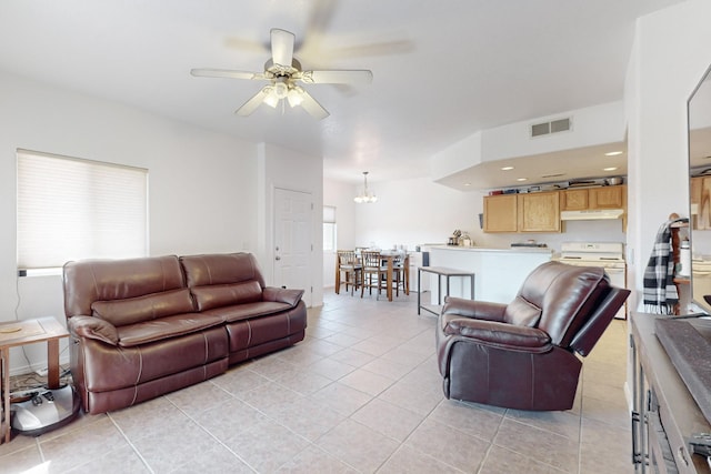 tiled living room with ceiling fan with notable chandelier