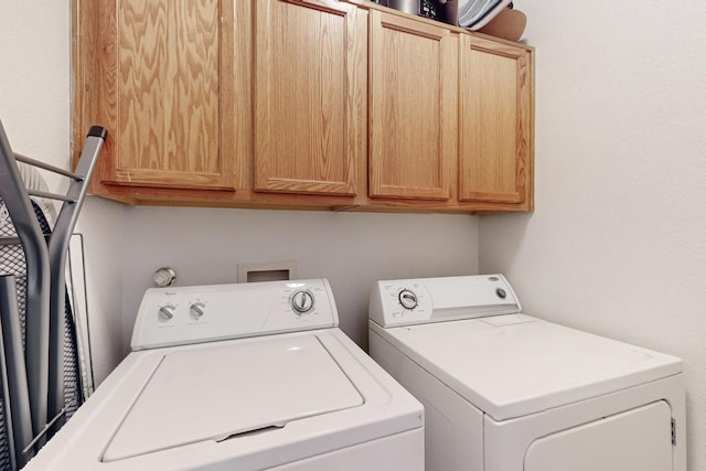 clothes washing area featuring washing machine and dryer and cabinets