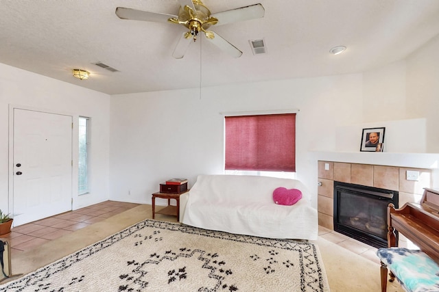 living room with a tile fireplace, ceiling fan, and light tile patterned floors