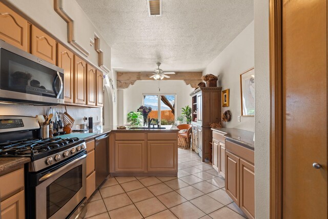 8008 Loma Larga Rd, Corrales, NM 87048 - kitchen featuring appliances with stainless steel finishes, a peninsula, a ceiling fan, a textured ceiling, and light tile patterned floors