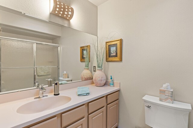 8008 Loma Larga Rd, Corrales, NM 87048 - bathroom featuring toilet, vanity, a shower stall, and a textured wall