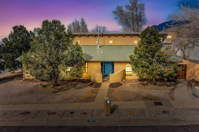 back of property at dusk with stucco siding