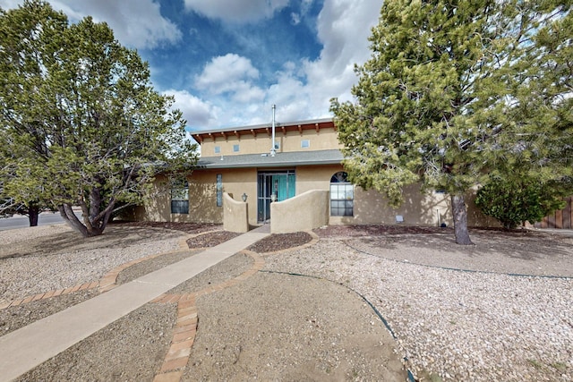 rear view of house featuring stucco siding and fence