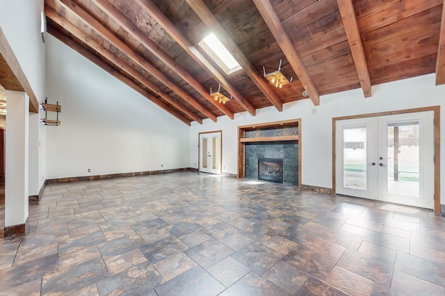 unfurnished living room with lofted ceiling with skylight, a tiled fireplace, french doors, baseboards, and wood ceiling