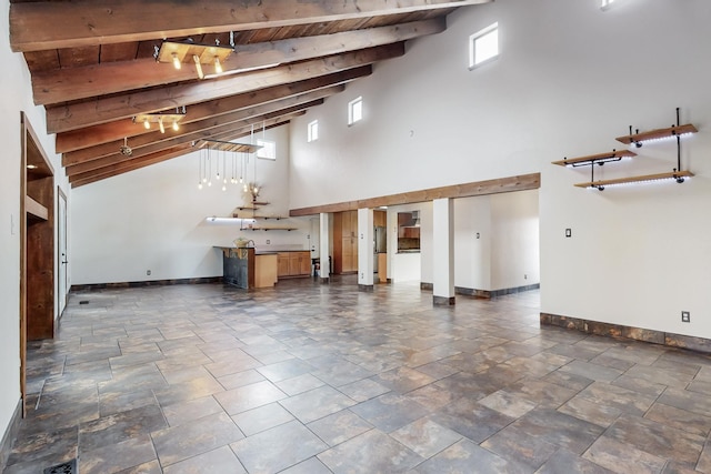 unfurnished living room with baseboards and beam ceiling