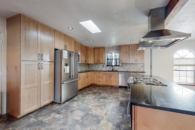 kitchen with island exhaust hood, a sink, backsplash, stainless steel appliances, and a skylight