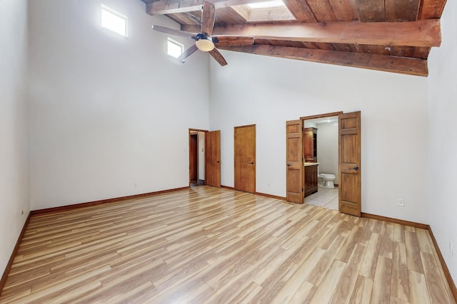 unfurnished bedroom featuring baseboards, beamed ceiling, a skylight, and light wood-style floors
