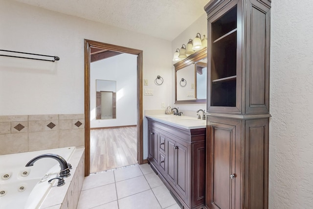 full bathroom featuring tile patterned flooring, a whirlpool tub, a textured ceiling, and a sink