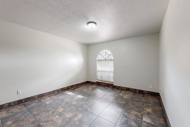 spare room featuring baseboards and a textured ceiling