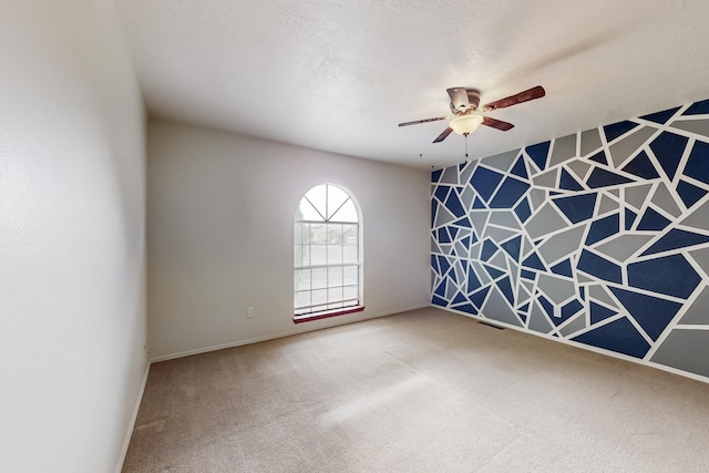 spare room with carpet flooring, a textured ceiling, ceiling fan, and an accent wall