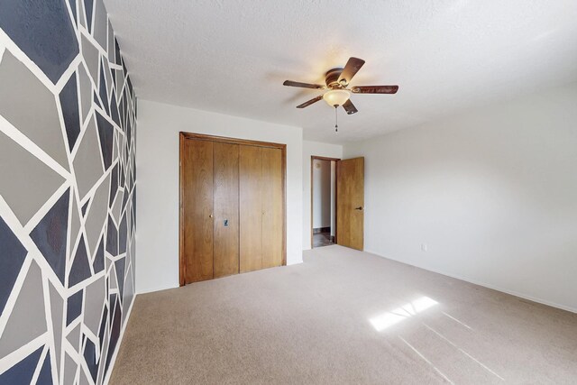 unfurnished bedroom with a closet, carpet flooring, a textured ceiling, and ceiling fan