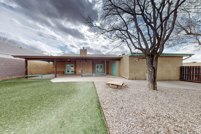 back of property with a lawn, a patio, fence, french doors, and a chimney