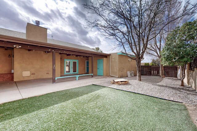rear view of house featuring french doors, a chimney, a patio, and fence